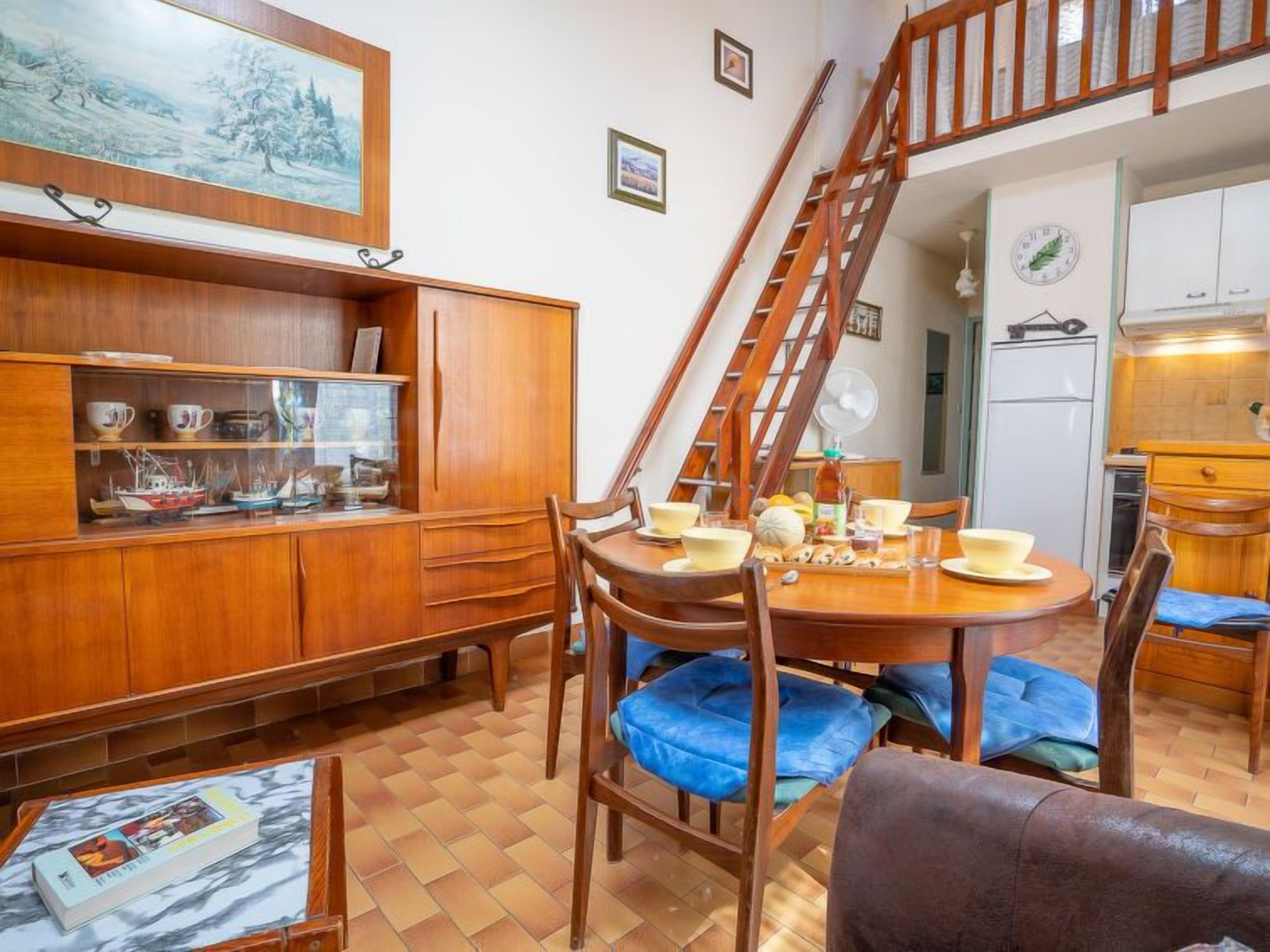 A dining area with a wooden table, chairs, and a staircase leading to an upper level.