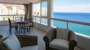 A room with a dining area, a sofa, and a view of the ocean. - Tor Serena by Interhome (Benidorm)