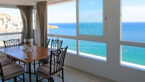 A room with a large window overlooking the sea, a wooden table with chairs, and a view of buildings in the distance. - Tor Serena by Interhome (Benidorm)