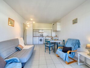 A compact living space with a sofa, a dining table, and a kitchen area.