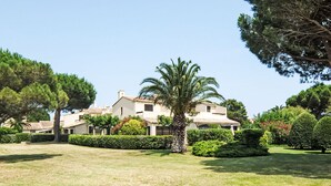 A large, two-story building with a tiled roof, surrounded by well-maintained lawns and various trees. - Les Catalanes du Golf by Interhome (Saint Cyprien)