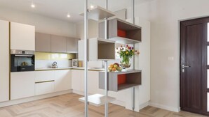 Eine moderne Küche mit weißen Schränken, einem eingebauten Ofen und einer Obstschale auf einem Regal.