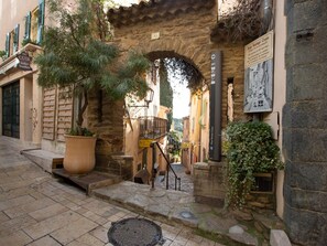 A stone archway leading to a building with a sign indicating it is Rue Rompi Cuou.