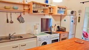 Kompakti keittiö, jossa on puinen työtaso, pesukone, liesi ja jääkaappi.