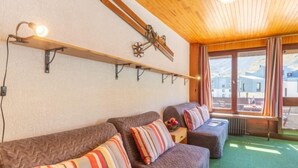 A cozy room with a wooden ceiling, a green carpet, and a sofa set with striped pillows. - Les Tufs (Val Claret) by Interhome (Tignes)