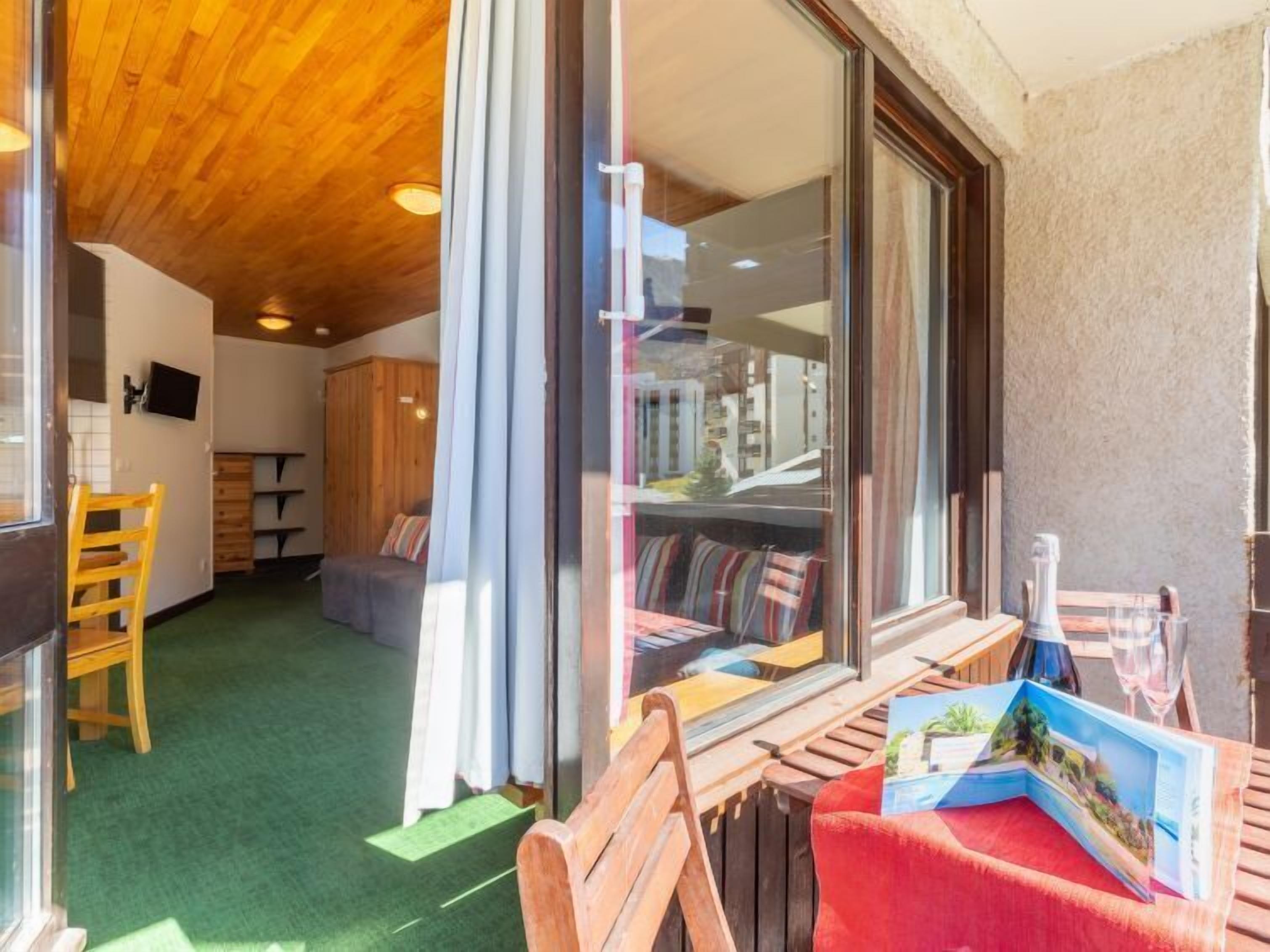 A cozy room with a wooden ceiling, a green carpet, and a window with a view of the city.