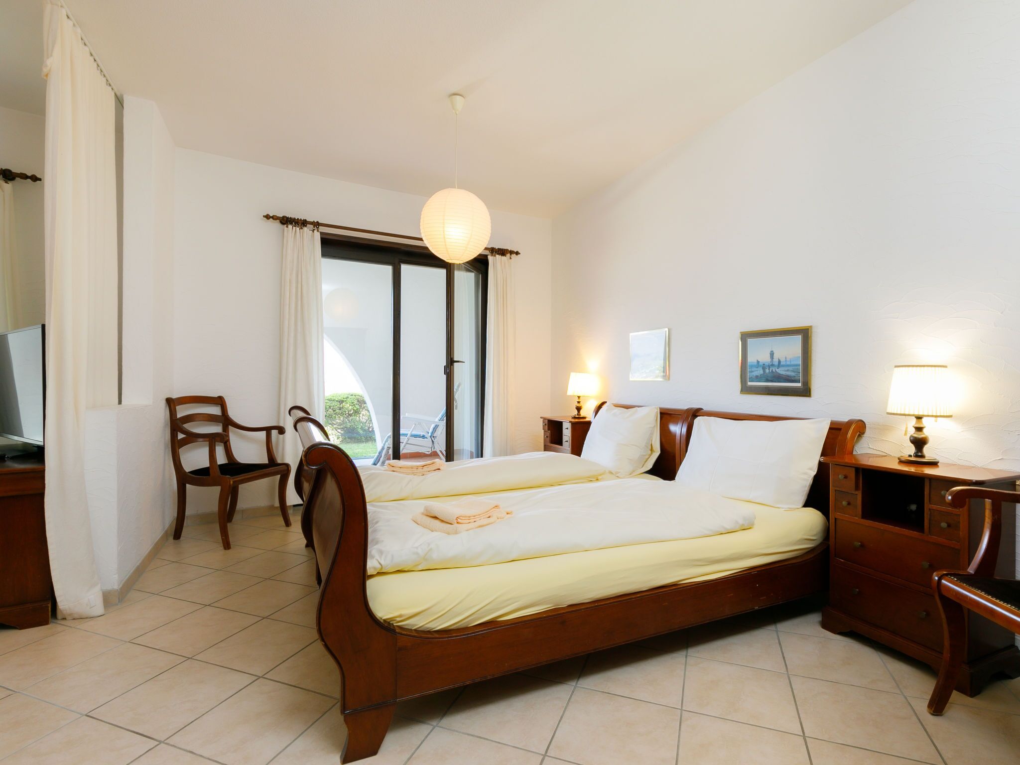 Une chambre d’hôtel avec un grand lit, une chaise, un bureau, une lampe et un téléviseur.