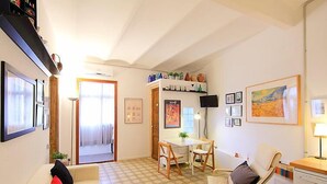 Een gezellige woonkamer met een bank, een eethoek met tafel en stoelen, en een keuken met een fornuis.