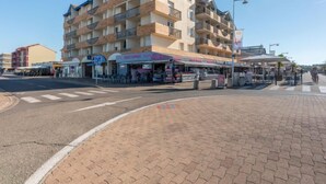 Ein mehrstöckiges Hotel mit Balkonen, einer Straße davor und Außenbestuhlung für Cafés.