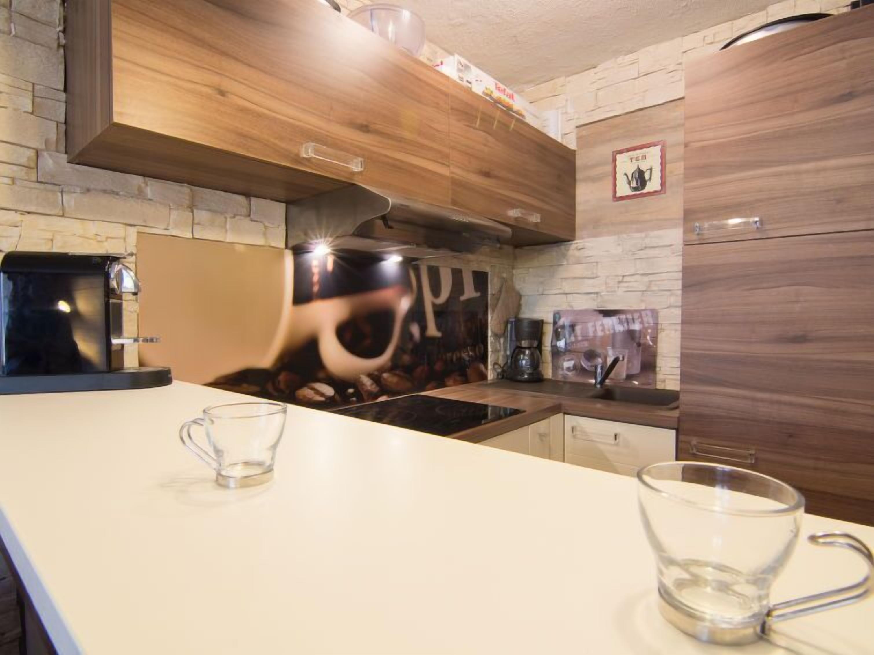 Eine moderne Küche mit Wandverkleidung aus Stein, Holzschränken und einer Kaffeemaschine.