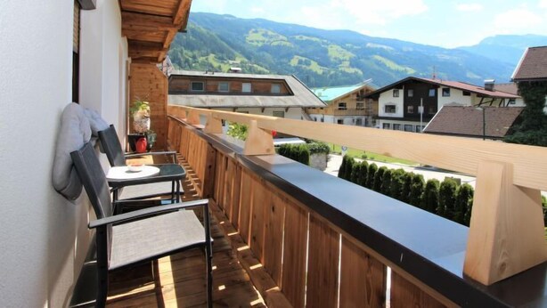 Un balcone in legno con vista sulle montagne e sulle case.