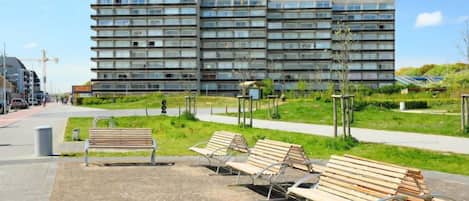 A modern building with multiple floors, a paved walkway, and several benches.
