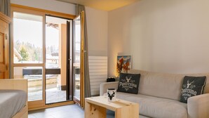 Een moderne woonkamer met een bank, een houten salontafel en uitzicht door een glazen deur op een terras.