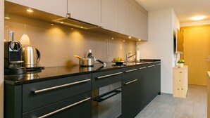 Een moderne keuken met zwarte kastjes, roestvrijstalen apparatuur en een houten kastje met een plant.