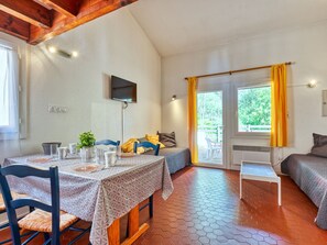 Una habitación acogedora con una mesa de comedor, sillas, cama y televisor montado en la pared.