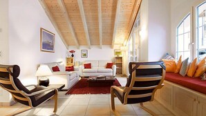 A spacious living room with a high ceiling, a white sofa set, two armchairs, a red rug, and a window with a view. - Apartment Aquila by Interhome (Zermatt)