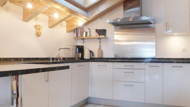 A modern kitchen with white cabinets, a stainless steel range hood, and a skylight above the countertop. - Apartment Aquila by Interhome (Zermatt)