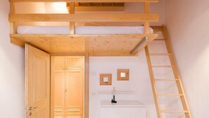 A compact room with a bunk bed, a white dresser, a ladder, and a door leading to another room. - Apartment Aquila by Interhome (Zermatt)
