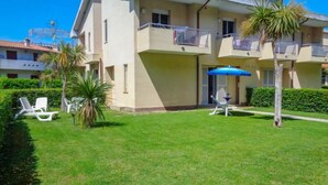 A residential building with a well-maintained lawn, outdoor seating area, and a blue umbrella. - Cerrano by Interhome (Silvi Marina)