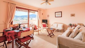 Ein gemütliches Wohnzimmer mit Essbereich, Deckenventilator und Blick auf die Stadt.