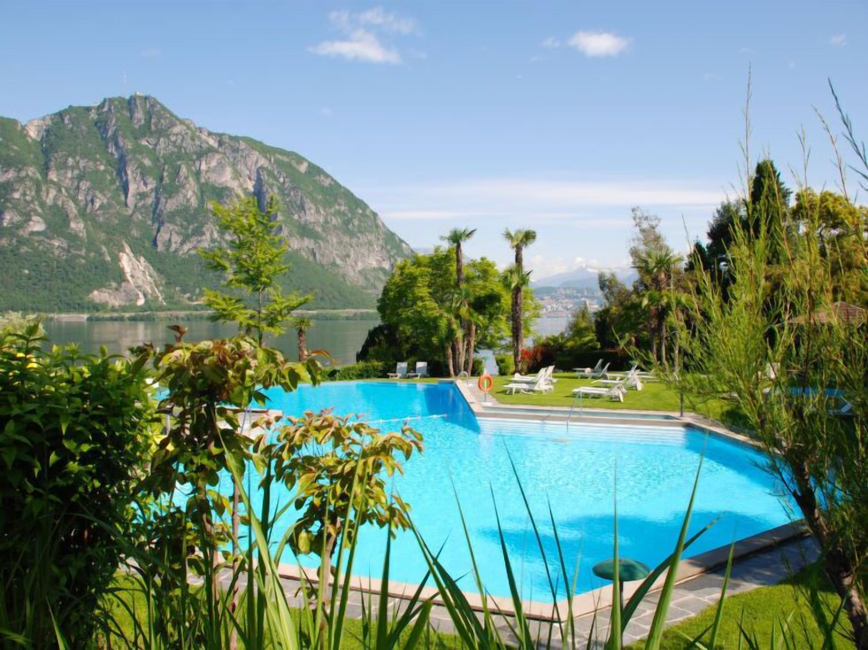 A swimming pool with a view of a mountain and a lake.