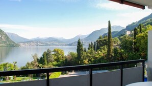 A balcony with a view of a lake, mountains, and greenery. - App. 511 by Interhome (Bissone)