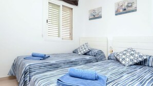A bedroom with two beds, striped bedding, and a window with shutters. - Apartment  Ronda by Interhome (L'Escala)