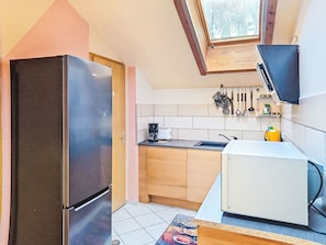 Een kleine keuken met een koelkast, een magnetron en een spoelbak.