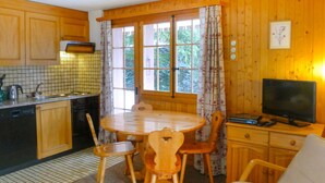 Interior de madeira com cozinha, sala de jantar e televisão.