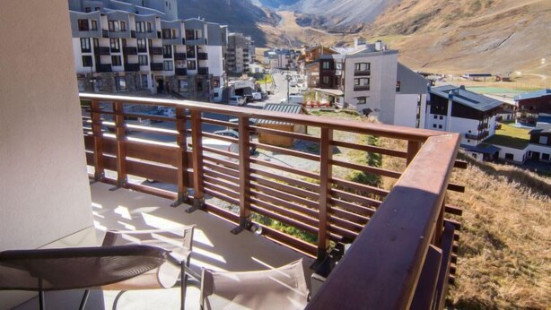 Un balcon offrant une vue sur une ville de montagne, avec des bâtiments modernes et un ciel dégagé.