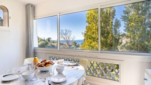 A dining area with a round table set for breakfast, overlooking a scenic view of trees and the sea. - Carpe Diem by Interhome (Rayol Canadel)