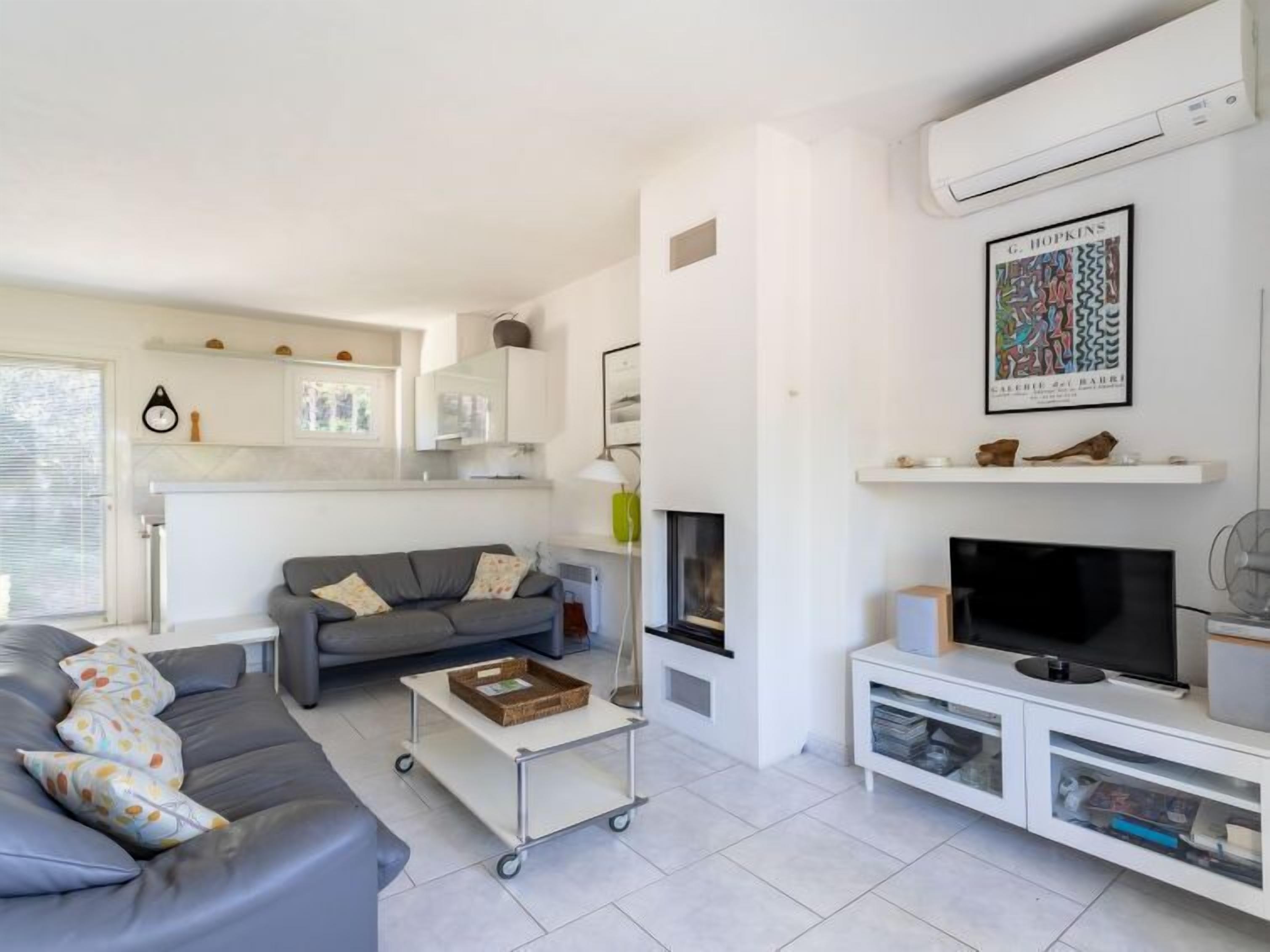 A modern living room with a grey sofa, a coffee table, a TV, and a fireplace.
