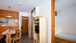 A compact room with a bed, a dining table with chairs, a kitchen area, and a TV. - Le Hameau du Borsat (Val Claret) by Interhome (Tignes)
