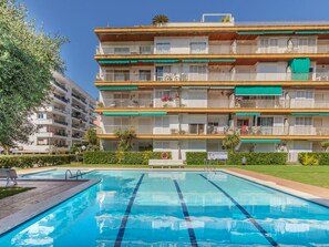 Um hotel de vários andares com varandas, piscina e um gramado bem cuidado.