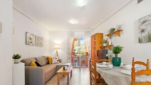 Un espacio habitable compacto con comedor, sofá, mesa y vistas a un balcón.
