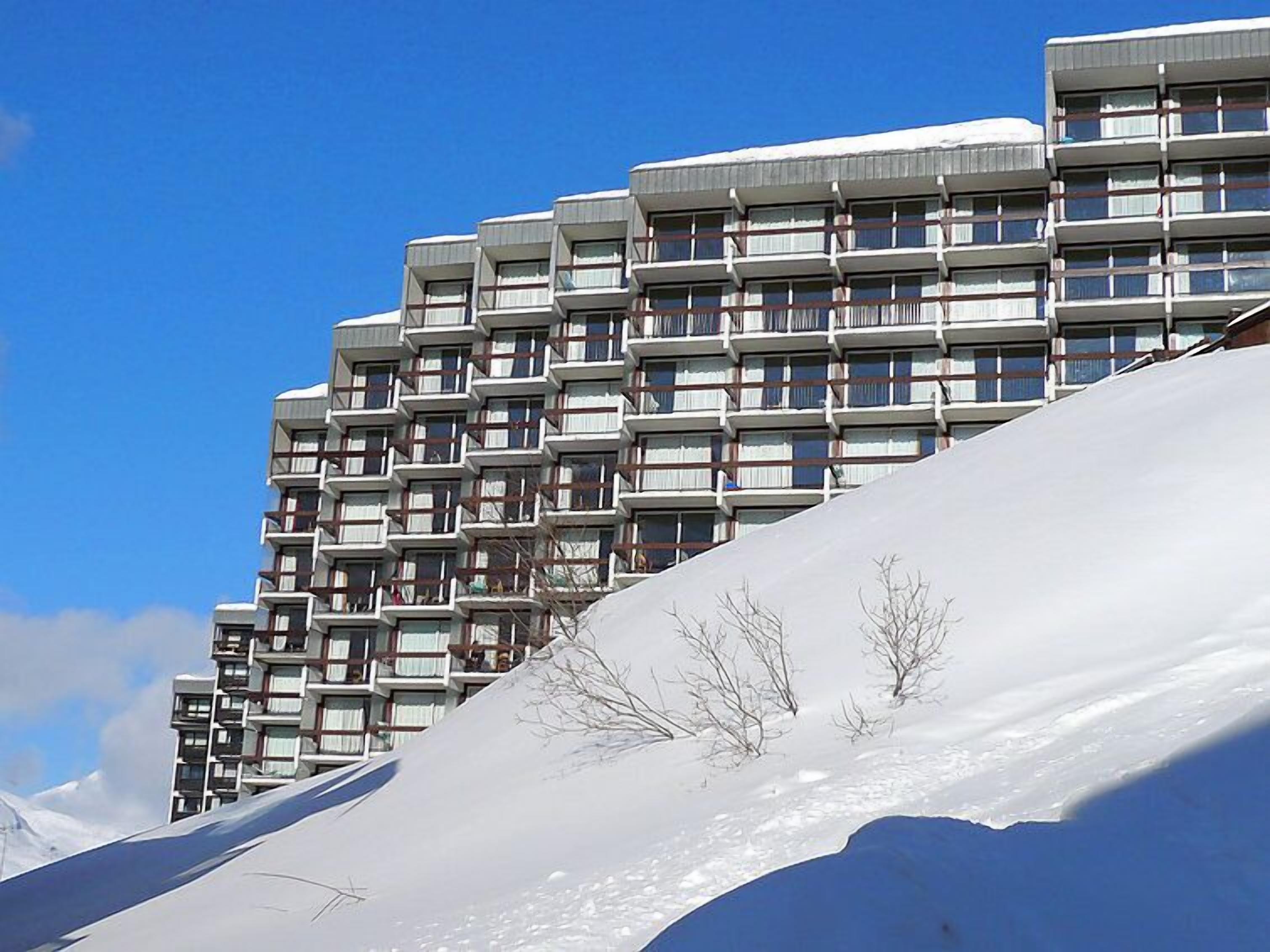 A multi-story hotel with balconies, set against a snowy landscape.