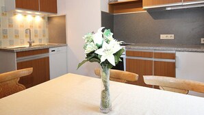 Una cocina moderna con armarios de madera, una encimera blanca y un florero con flores sobre la mesa.