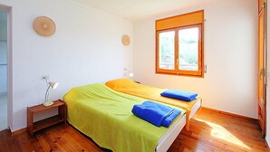 A bedroom with two beds, a window, a lamp, and a small table. - Las Alondras by Interhome (Roses)