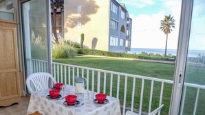 Un balcon avec une table dressée pour deux personnes, donnant sur une pelouse bien entretenue et un immeuble doté de balcons.