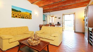 A living room with two yellow sofas, a wooden coffee table, and a painting of sunflowers on the wall. - Apartment Lucia by Interhome (Bucine)