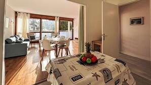Zona pranzo con tavolo imbandito per quattro persone, divano e vista su un balcone.