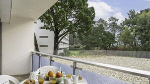 Un balcone con un tavolo apparecchiato per la colazione, con croissant, frutta e succo di frutta.