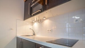 Une cuisine moderne équipée d’un évier en acier inoxydable, d’un four à micro-ondes et d’une hotte aspirante.