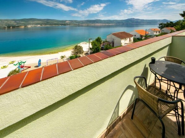 A balcony with a view of a beach and a calm sea.