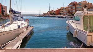 Un port de plaisance avec des bateaux amarrés, un ciel dégagé et des bâtiments en arrière-plan.