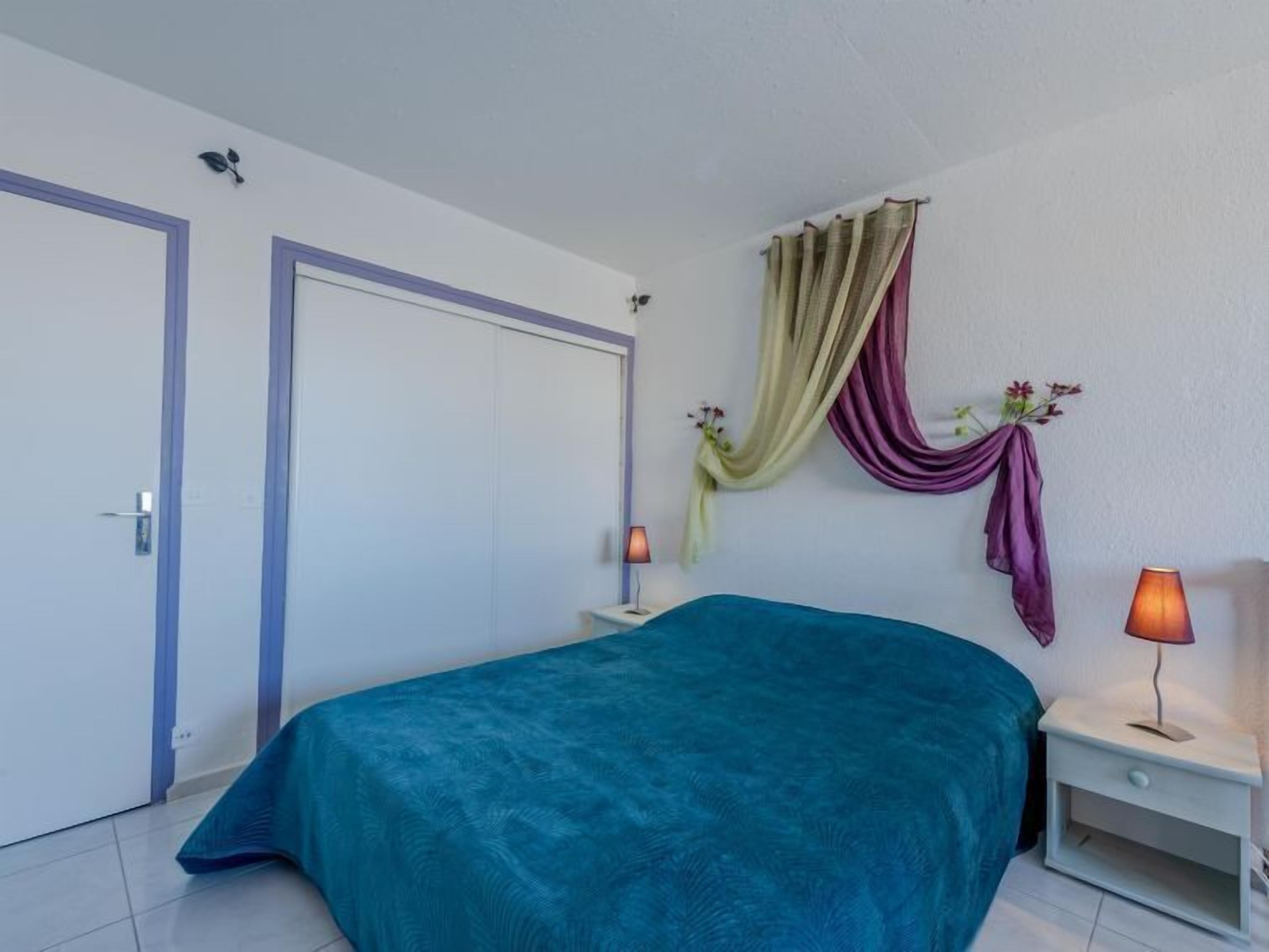 Camera da letto con un letto, due comodini, una lampada da parete e una porta.