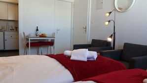 Habitació d'hotel amb un llit, un escriptori amb cadira, una taula de menjador amb cadira, un sofà, un mirall i una làmpada.