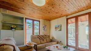 Una sala de estar acogedora con un sofá, una mesita de centro y una mesa de comedor. Se ve una ventana con vistas al exterior.