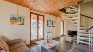 Una sala de estar acogedora con techo de madera, un sofá, una mesita de centro y un televisor.