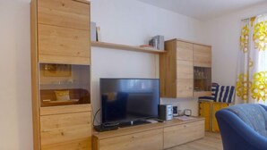 Ein modernes Wohnzimmer mit einem Holz-TV-Schrank, einem Flachbildfernseher und einem blauen Sofa.